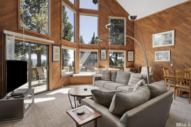 carpeted living room featuring high vaulted ceiling and wood walls