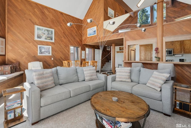 carpeted living room with high vaulted ceiling and wooden walls