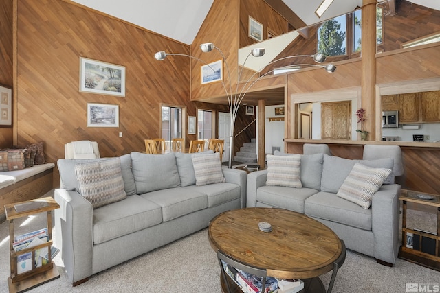 carpeted living room featuring high vaulted ceiling and wood walls