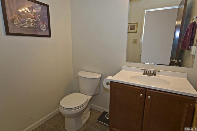 half bathroom featuring toilet, tile patterned flooring, vanity, and baseboards