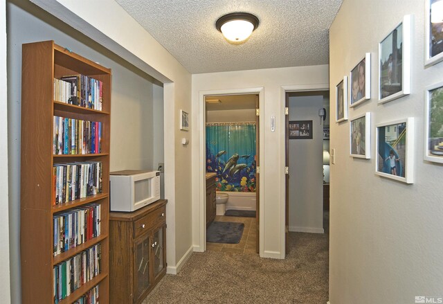 hall featuring carpet flooring, a textured ceiling, and baseboards