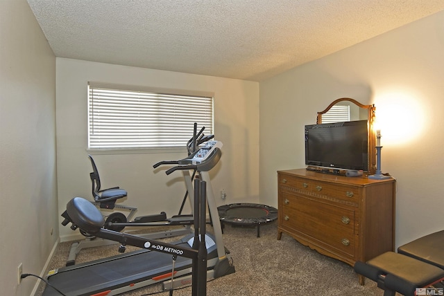 exercise room with a textured ceiling and carpet flooring