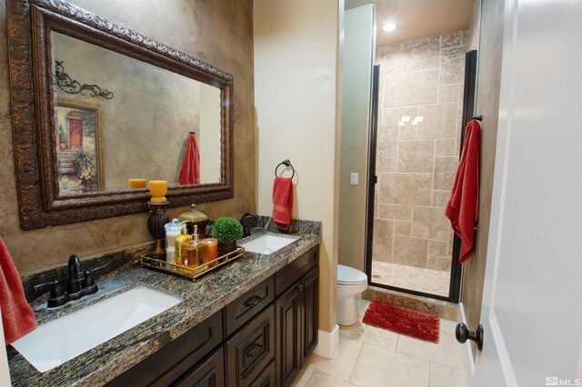 bathroom with an enclosed shower, toilet, dual bowl vanity, and tile patterned floors