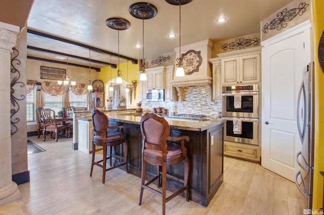 kitchen with decorative backsplash, stone countertops, appliances with stainless steel finishes, cream cabinetry, and light hardwood / wood-style floors