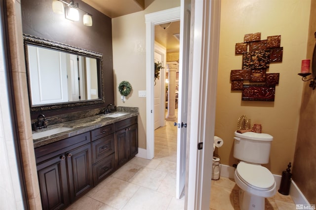 bathroom with tile patterned flooring, double vanity, and toilet