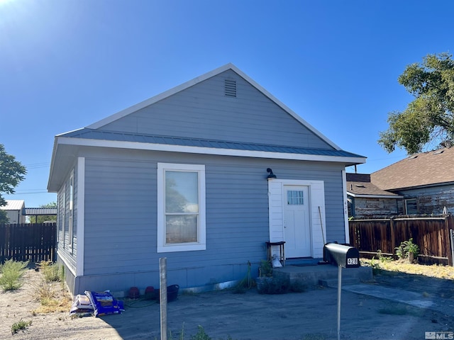 back of property with metal roof and fence