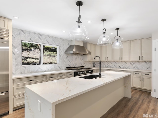 kitchen with a kitchen island with sink, hardwood / wood-style floors, tasteful backsplash, and wall chimney range hood