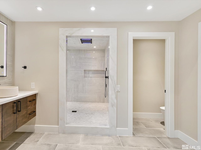 bathroom with tile patterned flooring, a tile shower, vanity, and toilet