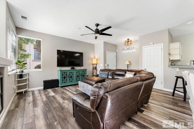 living room featuring sink, hardwood / wood-style floors, a fireplace, and ceiling fan