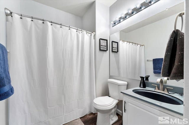 bathroom featuring a shower with shower curtain, toilet, wood finished floors, and vanity