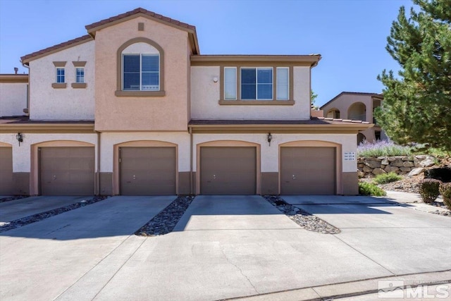 view of front of house featuring concrete driveway, an attached garage, and stucco siding