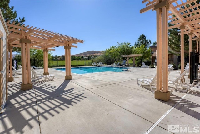 pool with a patio area, a mountain view, a pergola, and fence