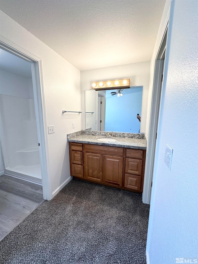 bathroom with ceiling fan, a textured ceiling, vanity, and hardwood / wood-style floors