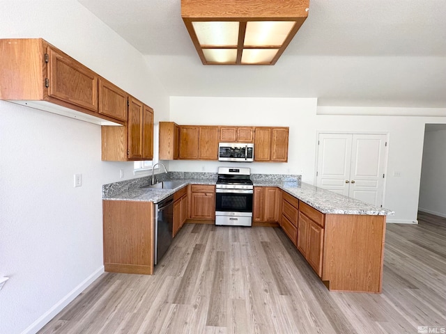 kitchen with sink, light wood-type flooring, appliances with stainless steel finishes, and light stone counters