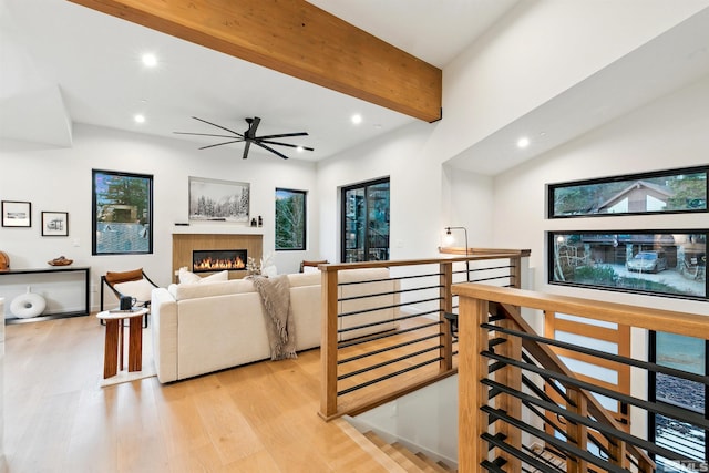 living area with light wood-style floors, recessed lighting, beam ceiling, and a fireplace