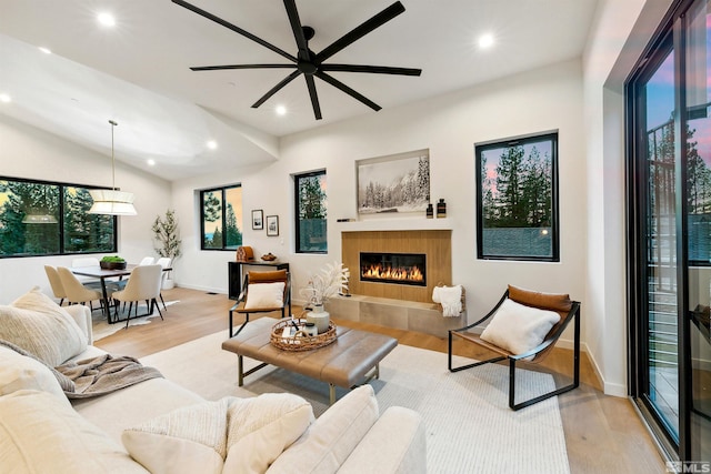 living room featuring recessed lighting, light wood-style flooring, a tiled fireplace, vaulted ceiling, and baseboards