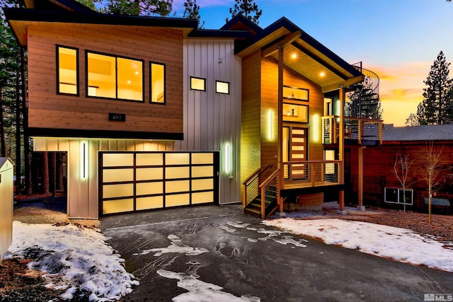 contemporary home with a garage, driveway, and board and batten siding