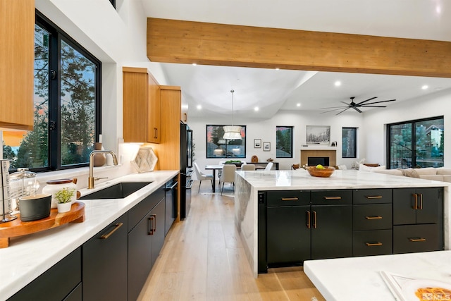 kitchen featuring light stone counters, recessed lighting, a sink, open floor plan, and beamed ceiling