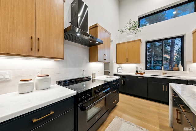 kitchen featuring black electric range, light countertops, dark cabinetry, and extractor fan