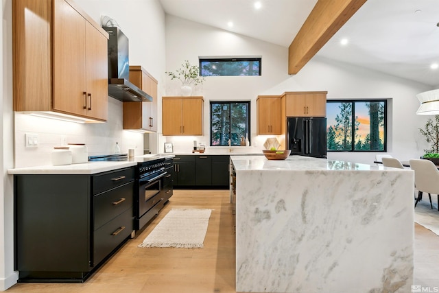 kitchen with a center island, black fridge with ice dispenser, dark cabinets, high end range oven, and wall chimney exhaust hood