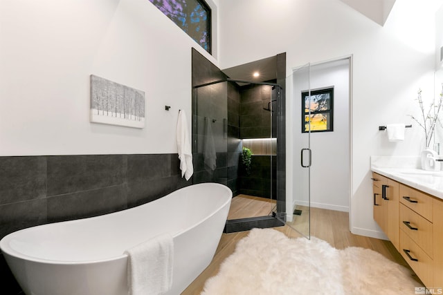 bathroom featuring a freestanding bath, a stall shower, vanity, and tile walls