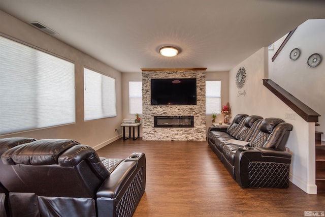 living room featuring a healthy amount of sunlight, a stone fireplace, and hardwood / wood-style flooring