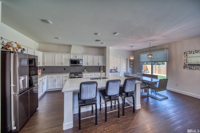 kitchen featuring appliances with stainless steel finishes, white cabinetry, sink, a center island with sink, and dark wood-type flooring