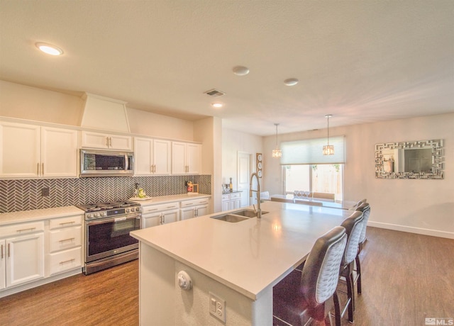 kitchen featuring appliances with stainless steel finishes, white cabinetry, tasteful backsplash, sink, and wood-type flooring