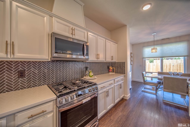 kitchen with appliances with stainless steel finishes, decorative backsplash, white cabinets, dark hardwood / wood-style flooring, and hanging light fixtures