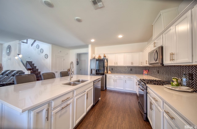 kitchen with sink, dark wood-type flooring, a kitchen island with sink, white cabinetry, and stainless steel appliances