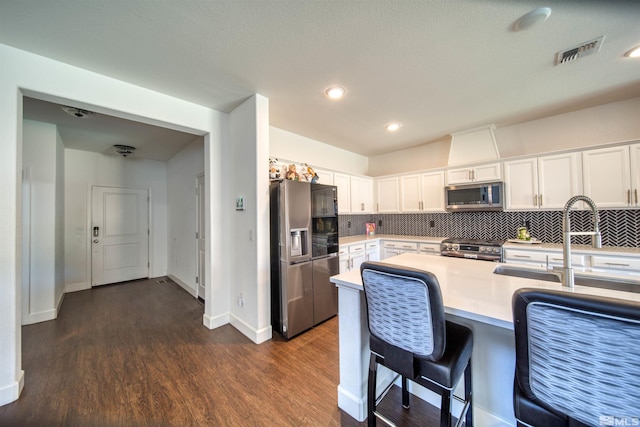 kitchen with appliances with stainless steel finishes, dark wood-type flooring, white cabinets, and backsplash