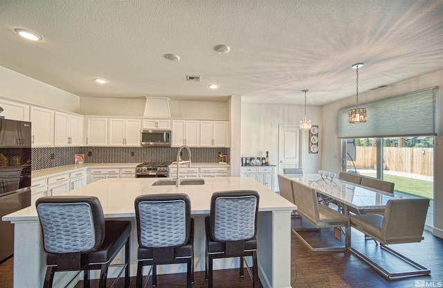 kitchen featuring white cabinetry, appliances with stainless steel finishes, tasteful backsplash, and an island with sink