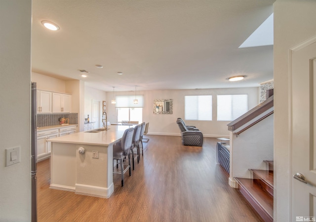 kitchen featuring a kitchen island with sink, light hardwood / wood-style floors, and white cabinetry