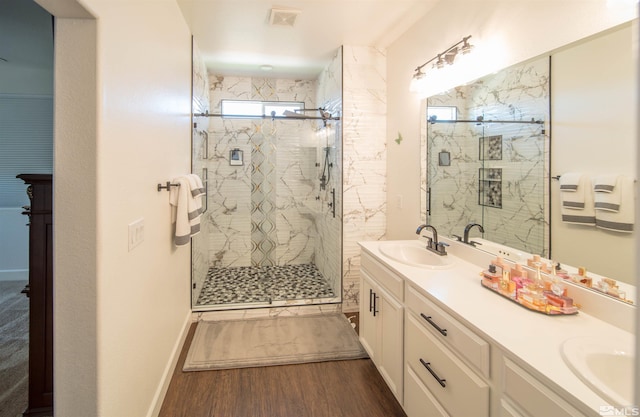 bathroom with hardwood / wood-style flooring, double vanity, and a shower with shower door