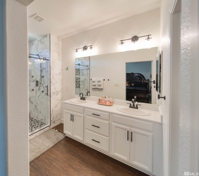 bathroom featuring wood-type flooring, double sink vanity, and a shower with shower door