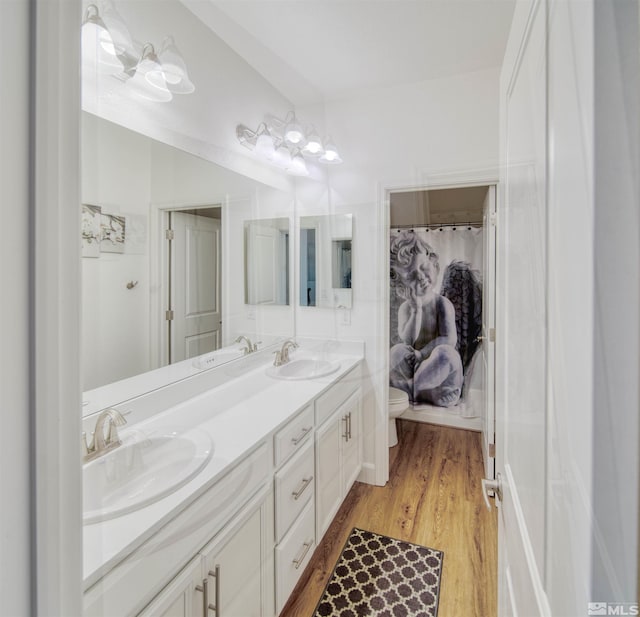 bathroom with toilet, double sink vanity, and hardwood / wood-style flooring