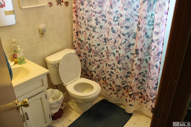 bathroom with toilet, vanity, tile walls, and tile patterned floors