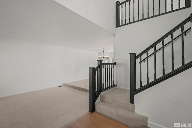 staircase with hardwood / wood-style flooring and an inviting chandelier