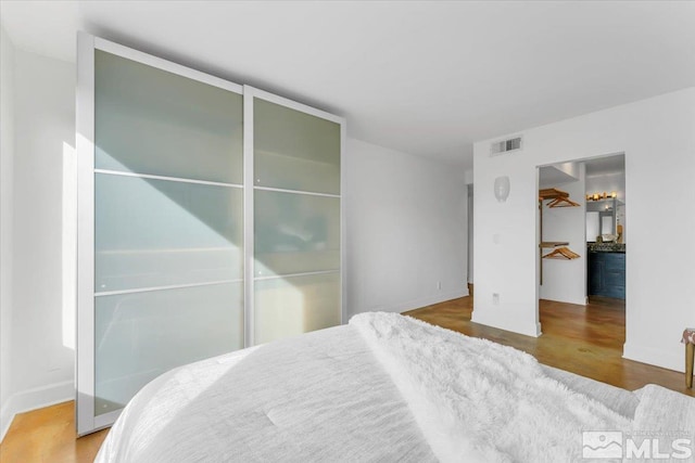 bedroom featuring a spacious closet, baseboards, visible vents, and a closet