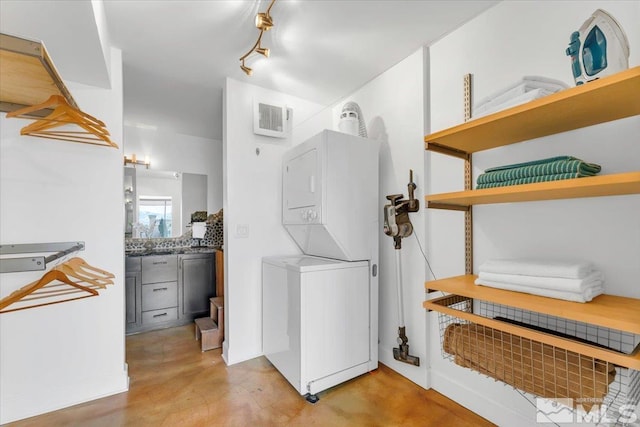 clothes washing area with visible vents, stacked washer / dryer, and laundry area