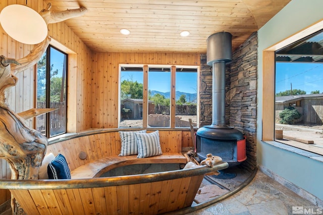 interior space with stone tile floors, wood ceiling, a wood stove, a mountain view, and recessed lighting