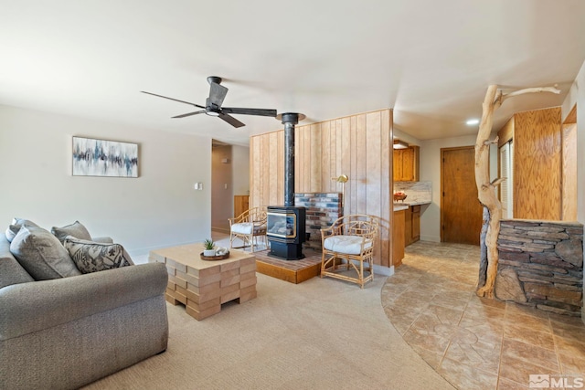 tiled living room with ceiling fan and a wood stove