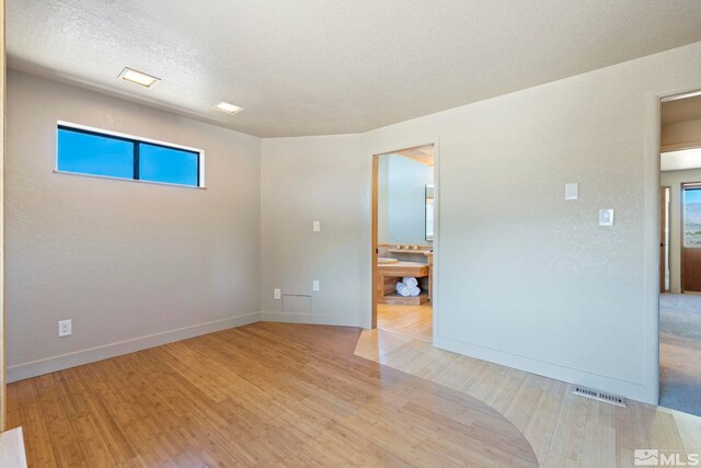 empty room featuring a textured ceiling and light hardwood / wood-style flooring