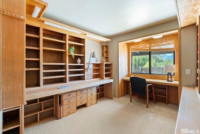 home office with light colored carpet and built in study area