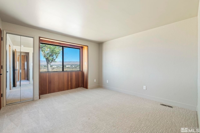 unfurnished room with baseboards, visible vents, and light colored carpet