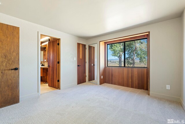 unfurnished bedroom featuring light carpet and ensuite bath