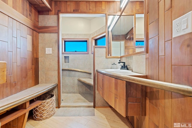 full bathroom with a stall shower, wood walls, and vanity