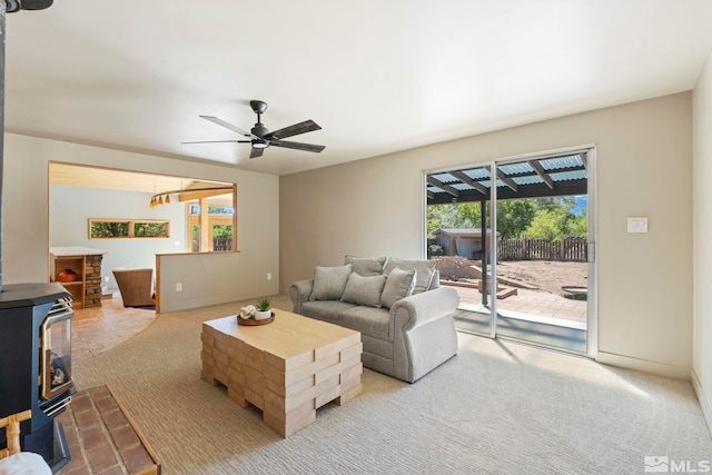 living room with ceiling fan, light colored carpet, and a wood stove