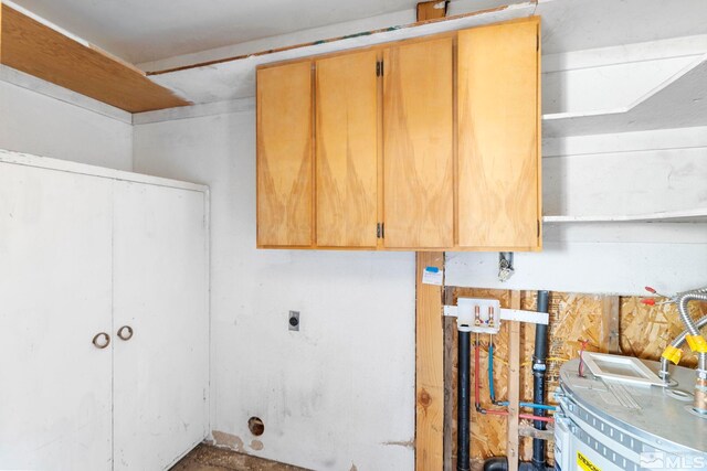 clothes washing area with electric dryer hookup, water heater, and cabinets