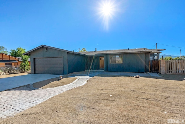 ranch-style house with an attached garage, driveway, and fence